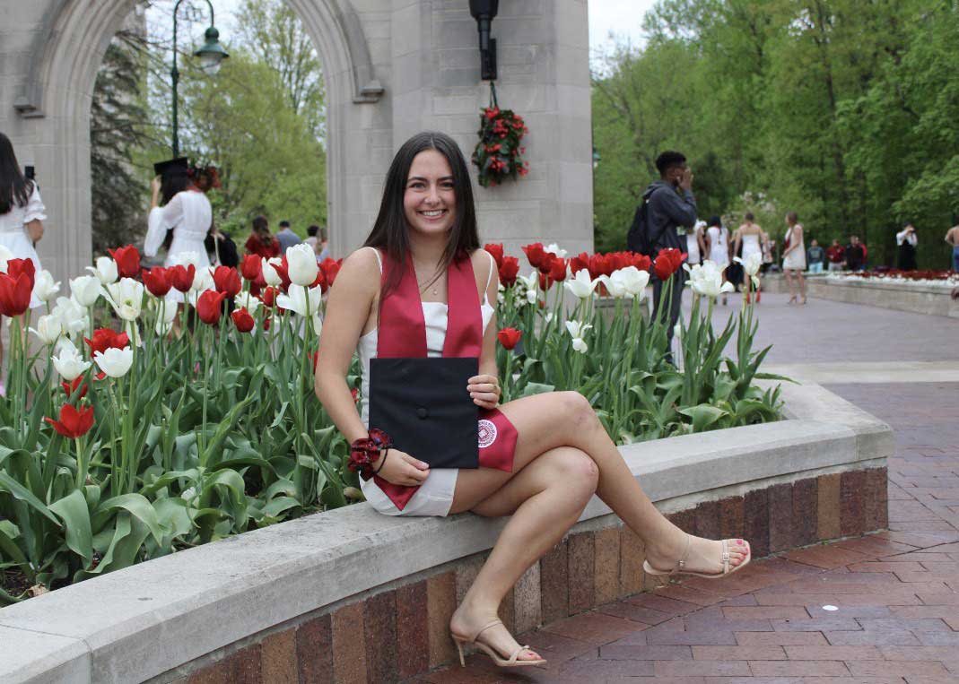 A photo of Anna Altavilla, who sits outdoors in front of the Sample Gates.